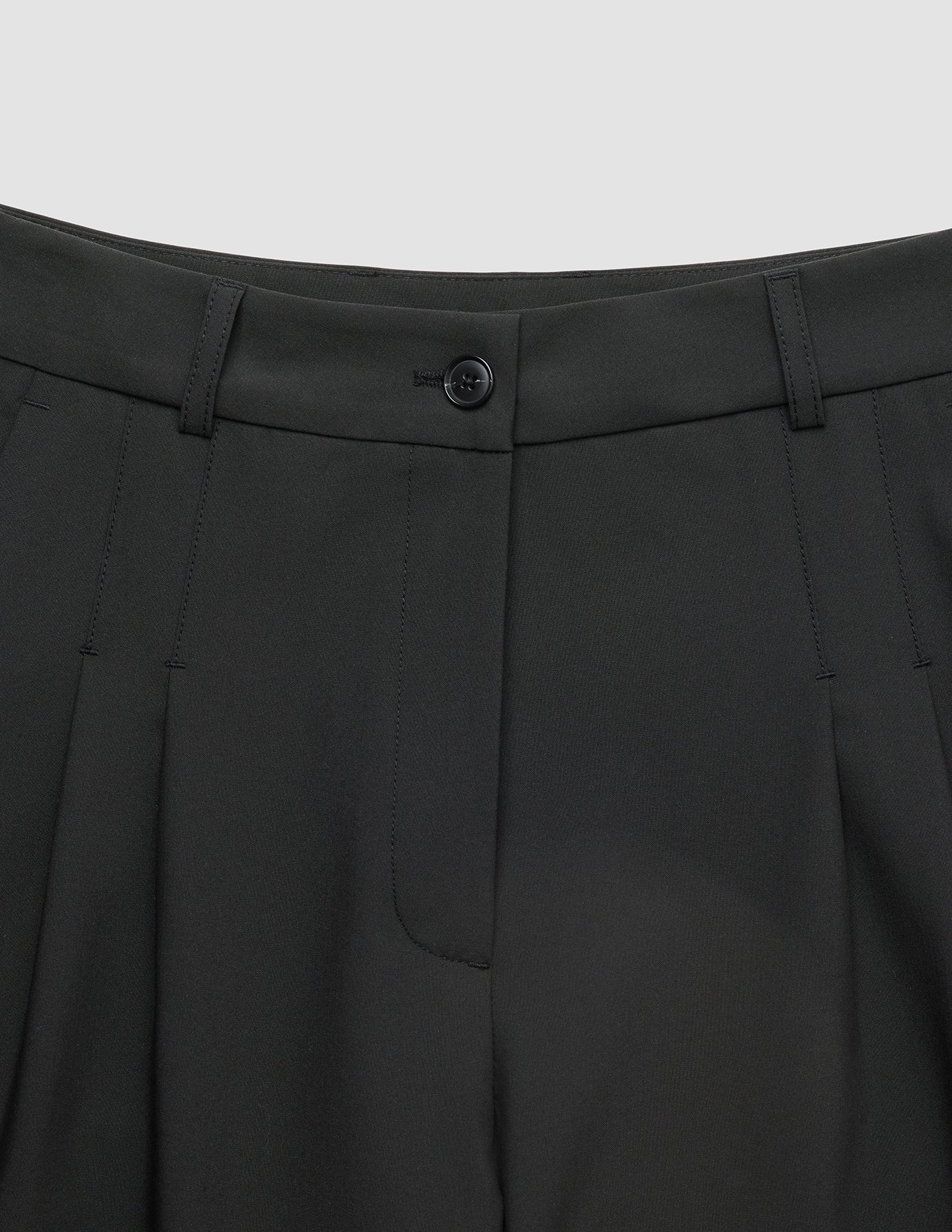 Närbild på midjebandet och den veckade framsidan på de svarta Avira Pants Wide Black-byxorna för dam.