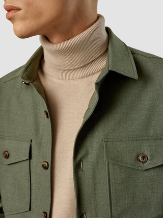 En man som bär en beige polotröja under en Essential Overshirt i färgen Nightfall Green Melange.