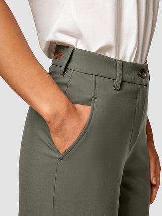 En person som bär byxorna ”Essential Pants Straight Dark Olive” med en hand i fickan.