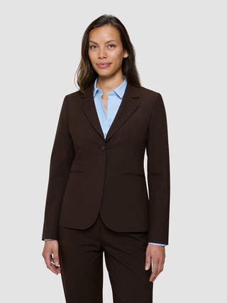 En kvinna som bär en ”Women’s Essential Fitted Blazer” i färgen Espresso över en ljusblå skjorta med knappar.