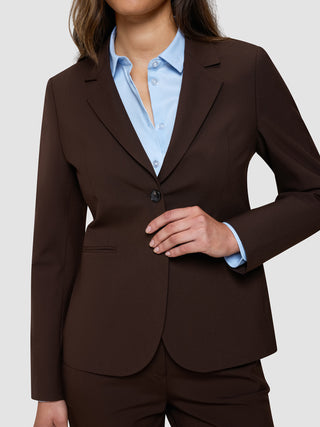 En person som bär en ”Women’s Essential Fitted Blazer” i färgen Espresso över en ljusblå skjorta med knappar.