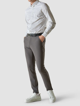 En man klädd i en vitrandig skjorta, Essential Pants Slim Grey och vita sneakers.