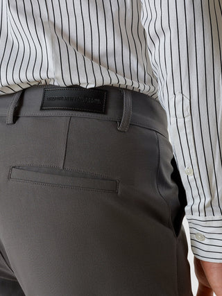 Essential-byxor i slim fit, gråa, med en ”Shaping New Tomorrow”-etikett i midjan, kombinerade med en vit randig skjorta.