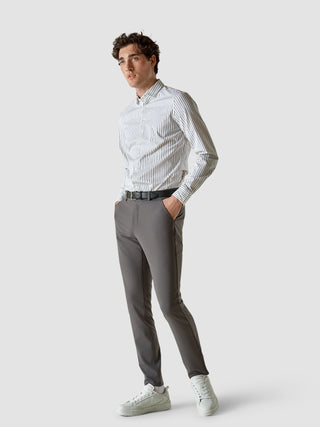 En man bär en vitrandig skjorta med knappar, Essential Pants Slim Grey och vita sneakers för en skandinavisk look.