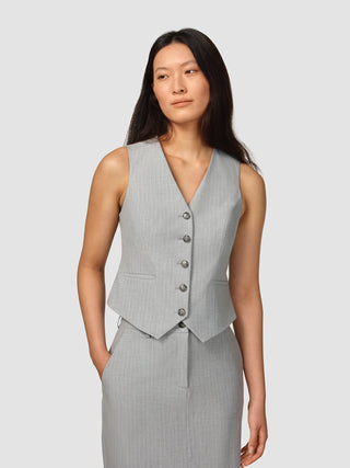 En kvinna klädd i en ljusgrå, knäppt Essential Short Vest Light Grey Pinstriped med 360°-stretch.