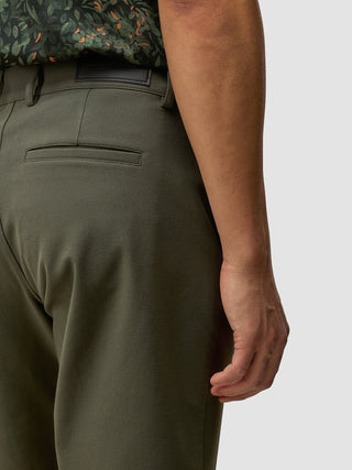 En person som bär GEN2™-shorts i dämpad grön färg och en mörk mönstrad skjorta.