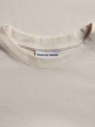 En benvit T-shirt i Heavy Box Fit med en ”Shaping New Tomorrow”-etikett i nacken och en avslappnad passform.