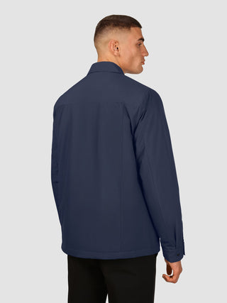 En man sedd bakifrån, klädd i en marinblå Hydro Jacket Dark Navy.
