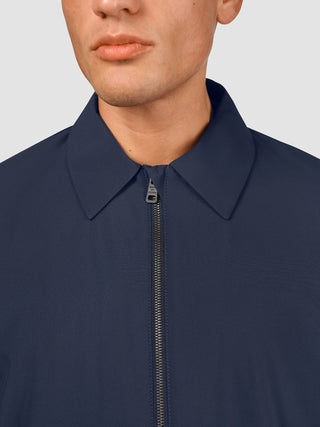 En man klädd i en Hydro Jacket Dark Navy med en minimalistisk skandinavisk design.