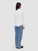 Bakifrånbild av en person som bär en vit Women’s Oxford Shirt White Orchid Slim instoppad i ljusblå jeans.