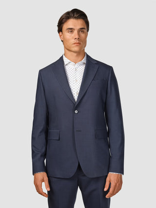 En man som bär en Tech Wool Suit Navy-jacka över en vit skjorta med ett fint mönster.