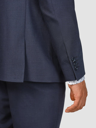Närbild på ärmen och ryggdetaljen på en Tech Wool Suit Navy som bärs över en mönstrad skjorta.
