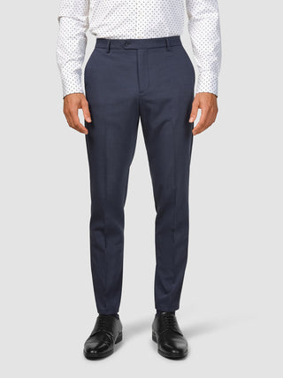 En man klädd i en mönstrad vit skjorta, en Tech Wool Suit Navy och svarta kostymskor.
