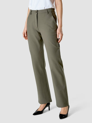 En person som bär byxor av modellen Essential Suit Straight i mörk olivgrön och svarta högklackade skor.