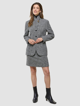 En kvinna visar upp Women Ashryn Short Skirt Domino Herringbone och den matchande kavajen tillsammans med svarta ankelstövlar.