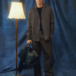 En man klädd i en mörkbeige overshirt från Atelier och matchande byxor, som håller i en svart läderduffelväska.
