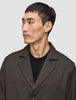 En man klädd i en mörkbrun Atelier Overshirt i brutet twill över en svart tröja.
