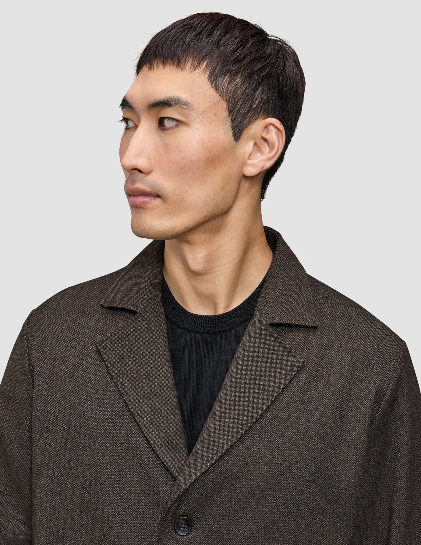 En man klädd i en mörkbrun Atelier Overshirt i brutet twill över en svart tröja.