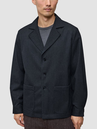 En person som bär en Atelier Overshirt Dark Navy i bruten twill med skårade kragar och två påsydda fickor.