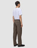 En man sedd bakifrån, klädd i en vit t-shirt och ett par löst sittande byxor i skandinavisk design, Atelier Pants Relaxed Dark Beige.
