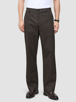 Atelier-byxor i avslappnad passform, mörkbruna i bruten twill, kombinerade med en vit skjorta och mörka läderskor.