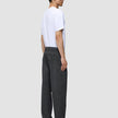 En person i profil bär en vit t-shirt och ett par Atelier Pants Relaxed i mörkgrått med avslappnad passform.
