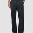 En person som bär marinblåa Atelier Pants Relaxed Dark Navy i bruten twill med avslappnad passform och svarta kostymskor.