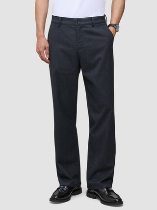En person som bär marinblåa Atelier Pants Relaxed Dark Navy i bruten twill med avslappnad passform och svarta kostymskor.