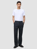 En man bär en vit T-shirt med rund hals och byxor av modellen Atelier Pants Relaxed Dark Navy i bruten twill.