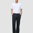 En man bär en vit T-shirt med rund hals och byxor av modellen Atelier Pants Relaxed Dark Navy i bruten twill.