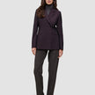 En kvinna klädd i en mörklila Women’s Avira Blazer Burgundy Berry över en grå polotröja och mörka byxor.