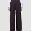 En person bär en vit skjorta med knappar och dambyxorna Avira Pants Wide i färgen Burgundy Berry, som har en avslappnad passform med vida ben.