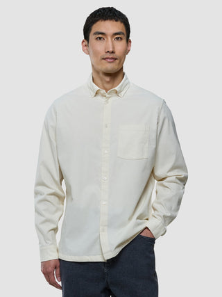 En man klädd i en benvit corduroy-skjorta och mörkgrå jeans.