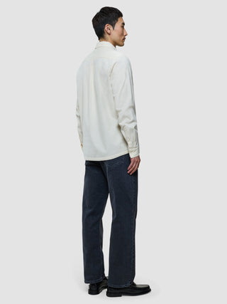 En man sedd bakifrån, klädd i en benvit corduroyskjorta och mörka jeans.
