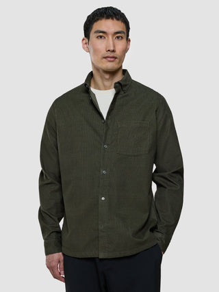 En man klädd i en corduroy-skjorta i färgen Nightfall Green över en vit t-shirt.