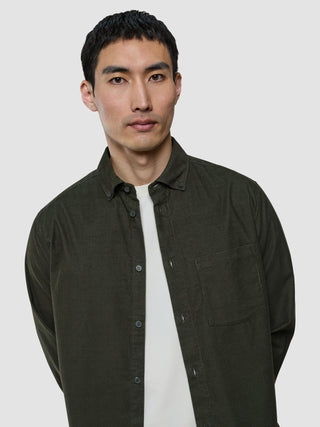 En man klädd i en corduroy-skjorta i färgen Nightfall Green över en vit t-shirt.