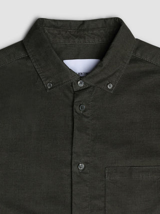 Närbild på en skjorta i corduroy i färgen Nightfall Green med bröstficka, som präglas av klassisk skandinavisk design.