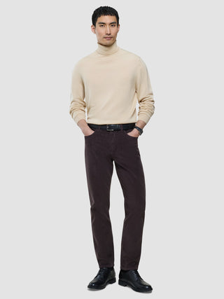 En man i en beige polotröja och corduroybyxor i färgen ”Deep Espresso”, med ett svart bälte och kostymskor.