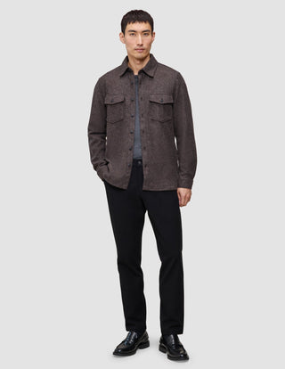 En man klädd i en dubbelskiktad ylleöverskjorta i sadelbrunt, en grå t-shirt, svarta byxor och svarta loafers.