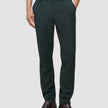 En person som bär mörkgröna Ease Pants Regular Northern Pine och bruna läderstövlar.