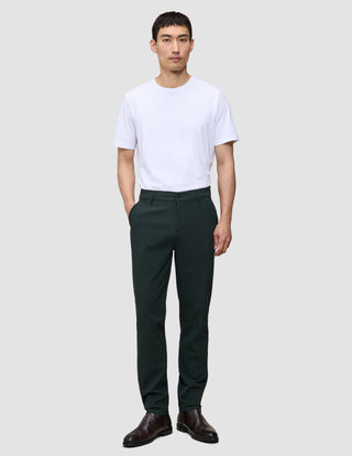En man i en vit t-shirt och Ease Pants Regular Northern Pine står vänd framåt.