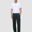 En person klädd i en vit t-shirt, mörka loafers och Ease Pants Relaxed Fit Northern Pine.