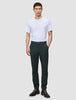 En person klädd i en vit t-shirt, mörkgröna Ease Pants Slim Northern Pine och mörkbruna läderstövlar.
