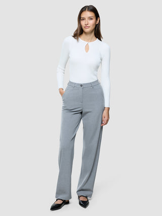 En kvinna klädd i en vit långärmad topp med nyckelhålsöppning och Women Ease Pants Straight Steel Melange.