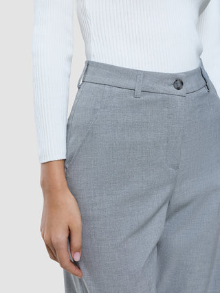 En person klädd i en vit långärmad tröja och byxor av modellen ”Women Ease Pants Straight Steel Melange” i skandinavisk design.