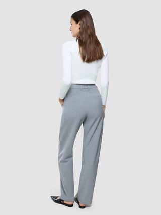 En kvinna sedd bakifrån, klädd i en vit långärmad topp och byxor av modellen ”Women Ease Pants Straight Steel Melange”.