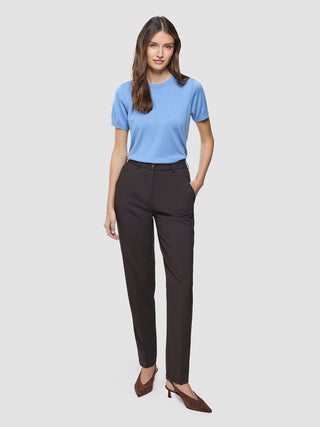 En kvinna visar upp en blå kortärmad tröja och ett par Women Ease-byxor i modellen Tapered i färgen Mocha Melange.