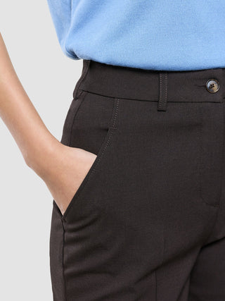 En person som bär ett par Women Ease-byxor i modellen Tapered Mocha Melange med sidficka och en blå topp.