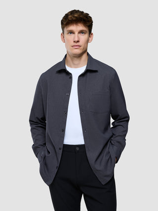 En man i en vit t-shirt, modellen ”Effortless Shirt Dark Grey”, och svarta byxor.