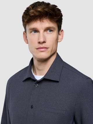 En man som bär en mörkgrå Effortless-skjorta över en vit t-shirt.